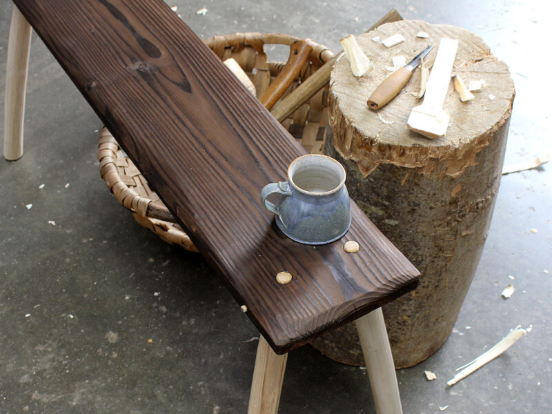 A ceramic cup sits on a handmade wooden bench in a woodwork workshop